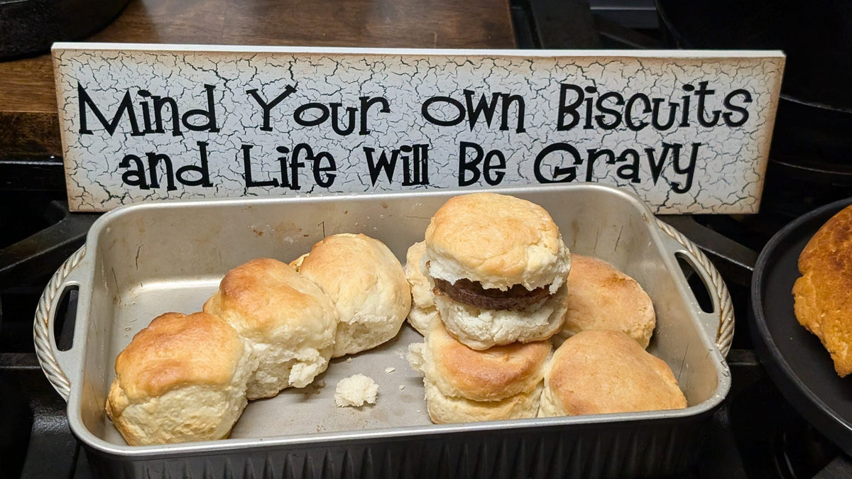 Biscuits in a pan beside a sign reading Mind Your Own Biscuits and Life Will Be Gravy